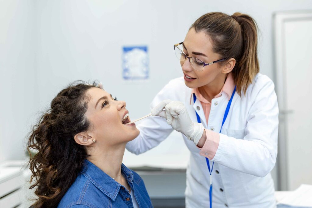 doctor-using-inspection-spatula-examine-patient-throat-ent-doctor-doing-throat-exam-woman-patient-opened-her-mouth-throat-checkup (1)